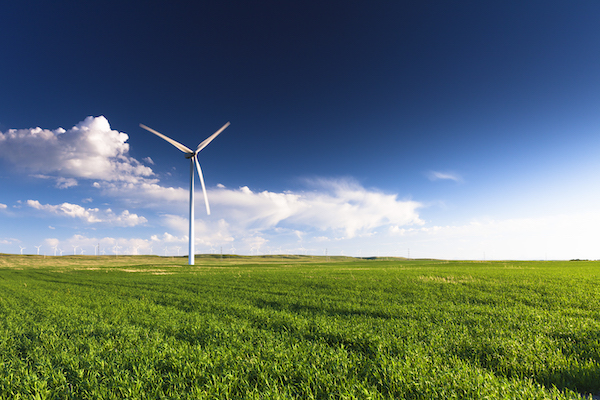 A wind turbine standing in a field.  Many more turbines can be seen in the distance.

copy space, blue sky, green, wind turbine, nobody, landscape, nature