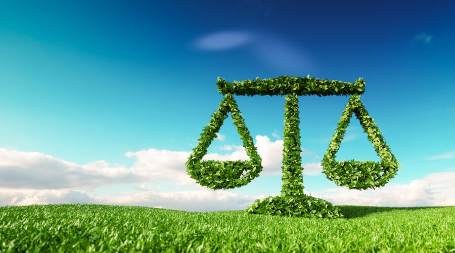 Eco friendly law, politics and eco balance concept. 3d rendering of scale icon on fresh spring meadow with blue sky in background.