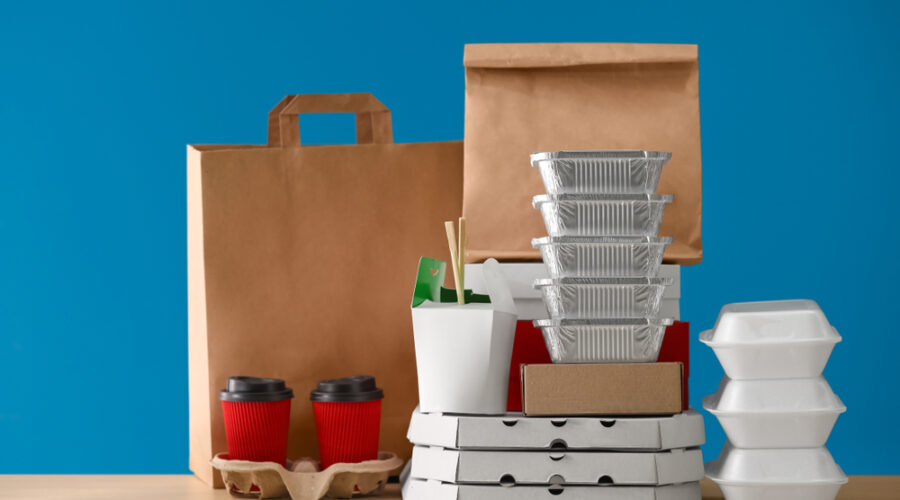 Different,Packages,And,Carton,Cups,On,Table,Against,Color,Background.